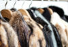 Close-up of hangers with hanging various assortment of fur winter coats. Background for a store of upper luxury clothes made of natural or eco fur